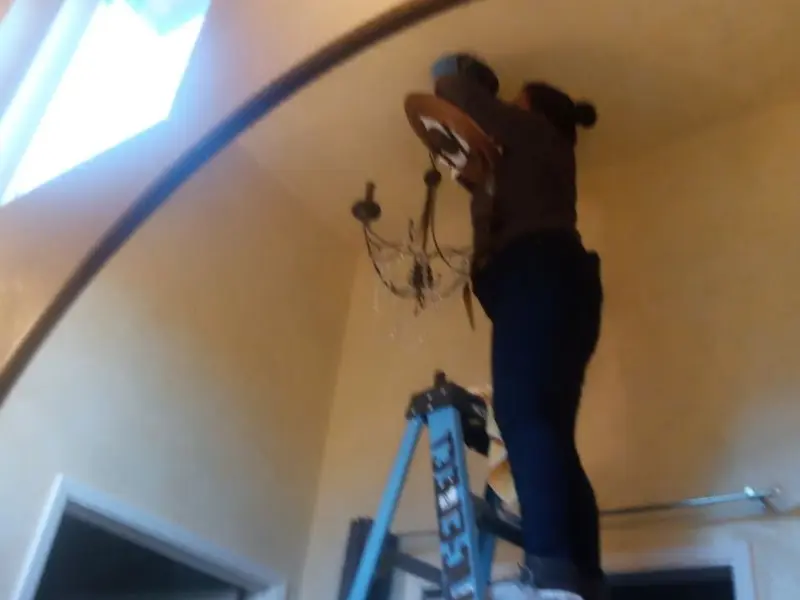 Electrician installing a chandelier in a Celina residence